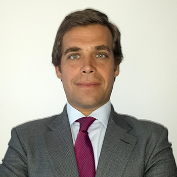 Homem em terno cinza e gravata vermelha, fundo branco.
