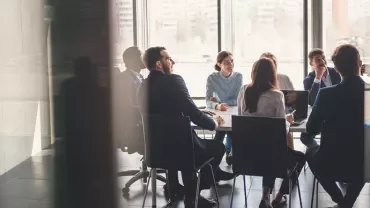 Pessoas em reunião numa sala de conferências iluminada.
