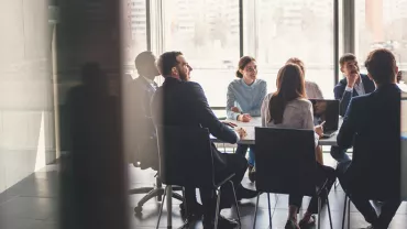 Pessoas em reunião numa sala de conferências iluminada.