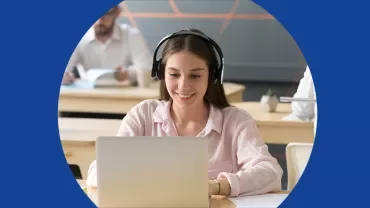 Mulher usando fones e laptop em sala de aula.