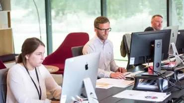 Pessoas trabalhando em computadores em um escritório moderno.