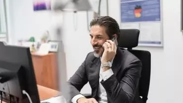 Homem sorrindo ao telefone no escritório.