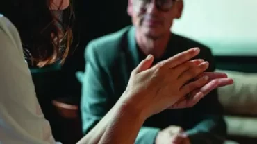 Pessoa gesticulando durante uma conversa em ambiente interno.
