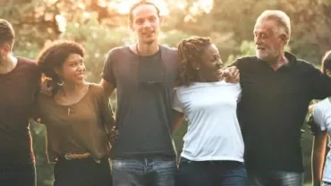 Grupo diversificado de pessoas sorrindo ao ar livre.