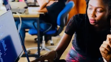 Duas pessoas trabalhando em frente a um computador em um escritório.