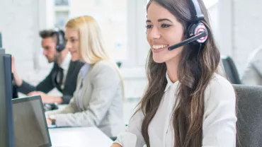 Funcionários em um escritório usando headset para atendimento.