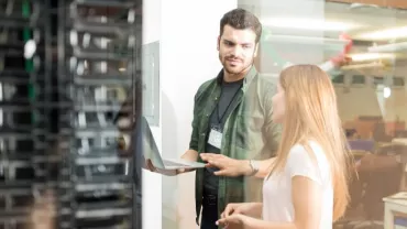 Dois profissionais discutem trabalho em um data center.