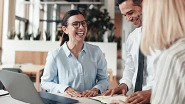 Grupo de colegas sorrindo em reunião de escritório.