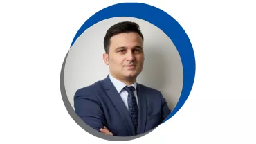 Homem de terno azul em retrato circular com fundo azul e cinza.