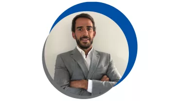 Homem de terno cinza, braços cruzados.