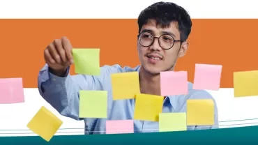 Homem organizando post-its coloridos em um quadro transparente.