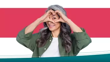 Mulher fazendo coração com as mãos em fundo colorido.