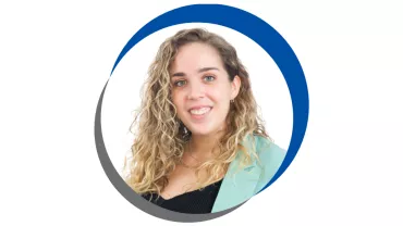 Mulher sorrindo com casaco verde claro e cabelo cacheado.