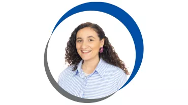 Mulher sorridente com cabelo cacheado em uma moldura circular azul e cinza.