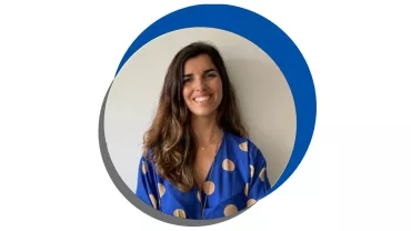 Mulher sorridente com blusa azul de bolinhas.