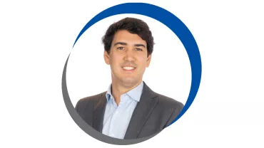 Homem em terno sorrindo, dentro de círculo azul e cinza.