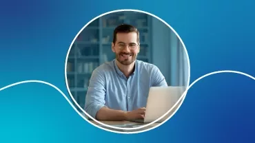 Homem sorrindo usando laptop em fundo azul.