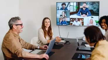 Uma equipa híbrida a trabalhar em conjunto numa reunião, utilizando competências de liderança para melhorar a produtividade dos colaboradores.