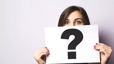 Mulher segurando cartaz com ponto de interrogação.