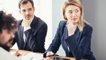 Pessoas em reunião de negócios, algumas olhando para o lado.