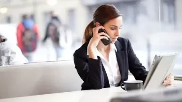 Mulher em um café, usando celular e tablet.