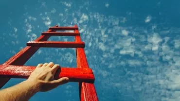 Mão segurando uma escada vermelha contra o céu azul.