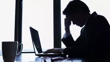 Homem preocupado sentado em frente ao laptop.