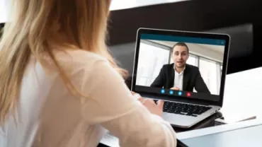 Mulher em videochamada com homem em laptop.