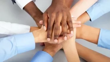 Mãos de várias pessoas unidas em sinal de colaboração.