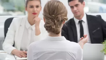 Entrevista de emprego com três pessoas em uma sala de escritório.
