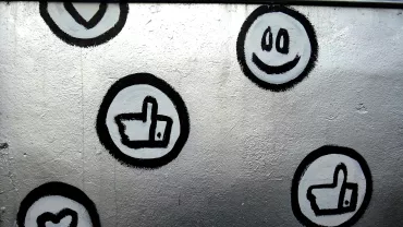 Grafite de ícones de coração, curtir e sorriso em parede.