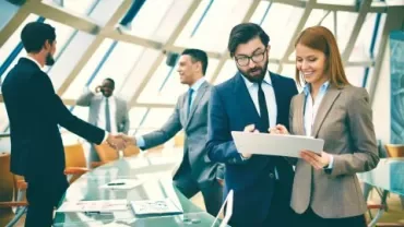 Executivos discutindo relatório em uma sala de reuniões moderna.