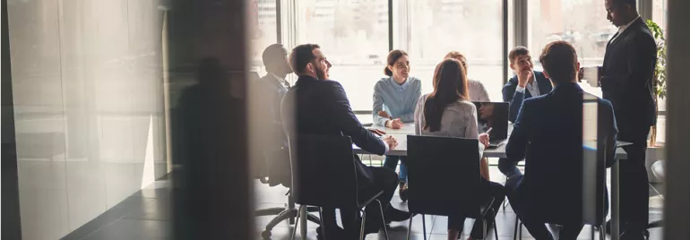 Pessoas em reunião numa sala de conferências iluminada.