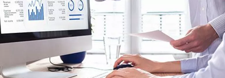 Profissionais analisam relatório financeiro em computador.