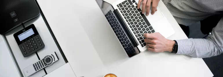 Pessoa trabalhando no laptop com café ao lado.