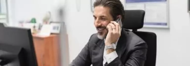 Homem sorrindo ao telefone no escritório.