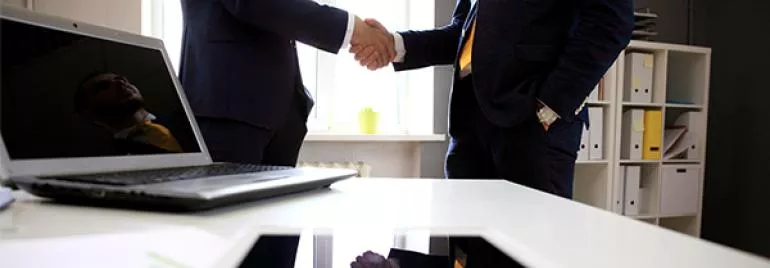 Dois homens de negócios apertando as mãos em um escritório.