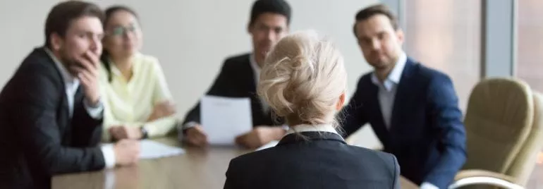 Reunião de negócios com cinco pessoas em volta de uma mesa.