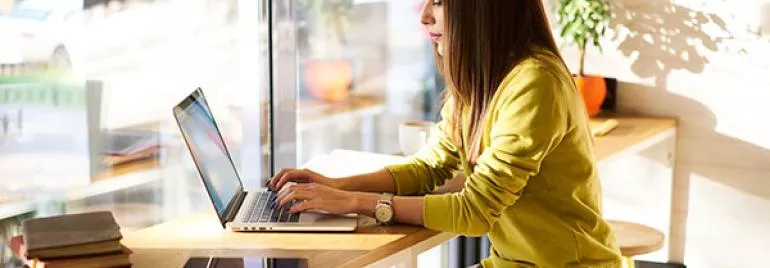 Mulher usando um laptop numa cafeteria.