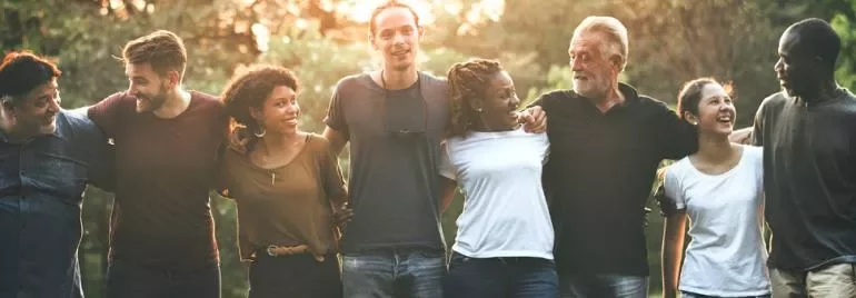 Grupo diversificado de pessoas sorrindo ao ar livre.