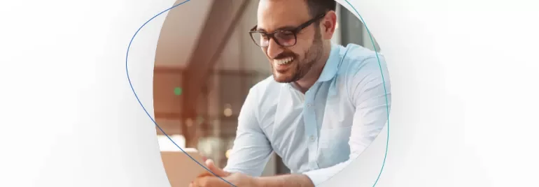Homem sorridente com óculos e camisa azul clara, segurando um tablet.