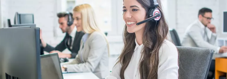 Funcionários em um escritório usando headset para atendimento.