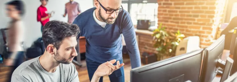 Dois homens trabalhando em frente ao computador.