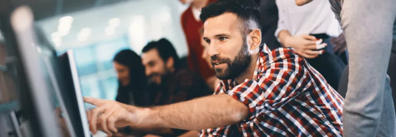 Grupo de pessoas em um escritório colaborando em um projeto no computador.