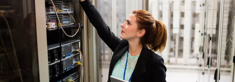 Técnica em data center ajustando servidores.