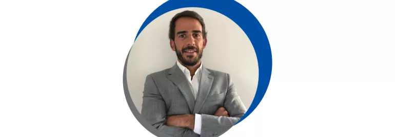 Homem de terno cinza, braços cruzados.
