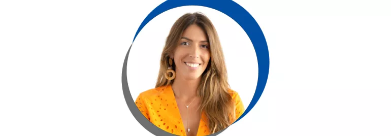 Mulher sorrindo, vestindo camisa laranja, cabelo castanho.