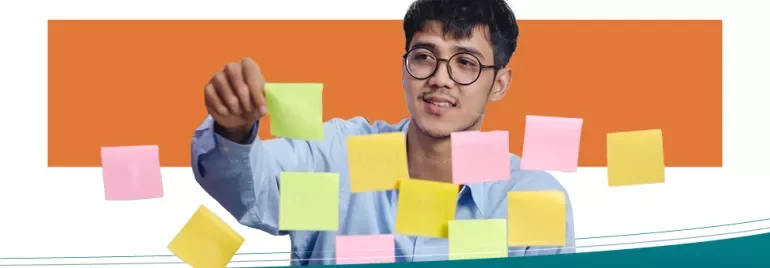 Homem organizando post-its coloridos em um quadro transparente.
