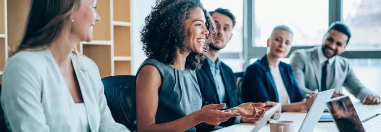 Grupo de pessoas em reunião de trabalho, sorrindo.