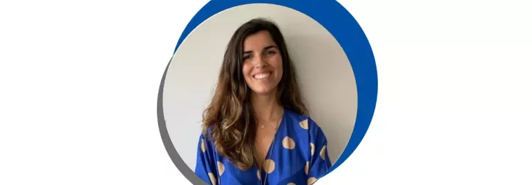 Mulher sorridente com blusa azul de bolinhas.